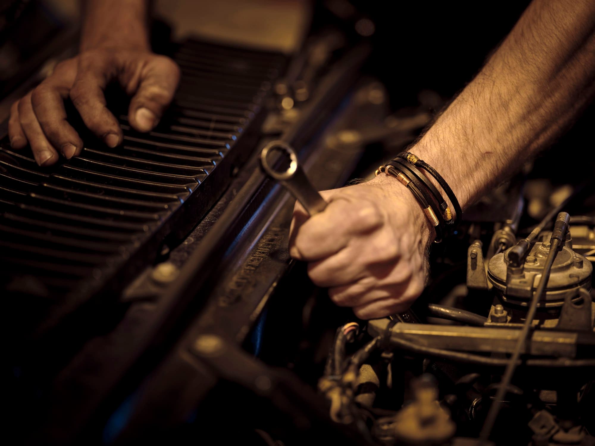 Mechanic's hands working on an engine with a spanner